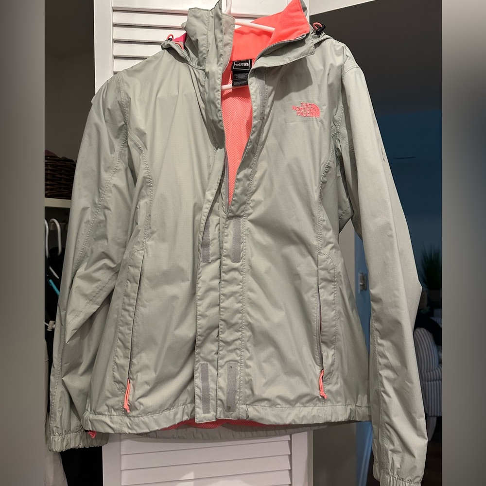 Khaki north face rain jacket with bright pink lining. Black mark on left sleeve.